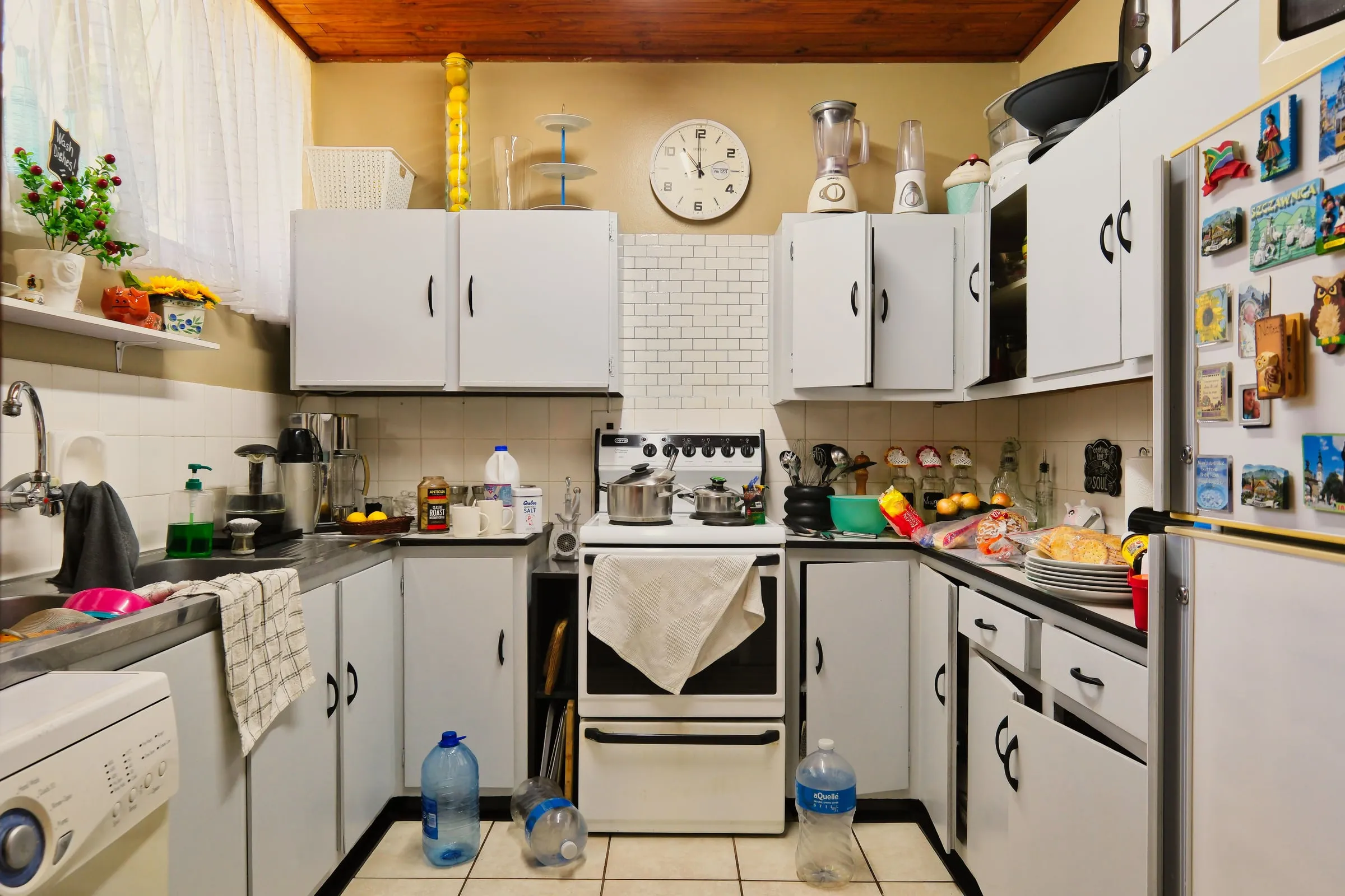 A kitchen counter mid-week: unopened post, a laptop, mugs and paperwork